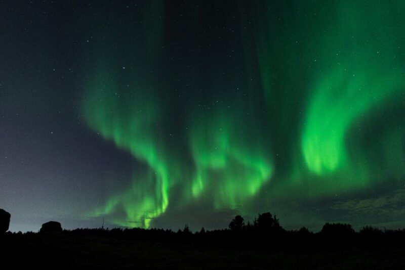 Un espectacular cielo nocturno en Islandia cubierto por intensas ondas de auroras boreales verdes.