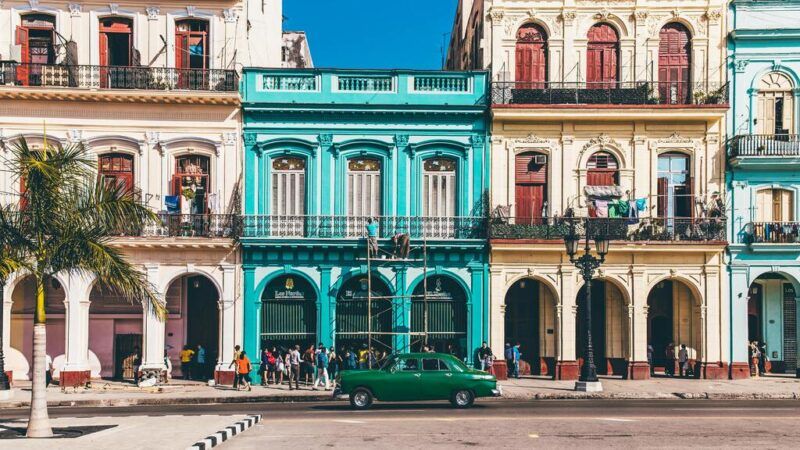 Un edificio colonial de color azul brillante rodeado de otras fachadas coloridas en una calle de La Habana, Cuba.