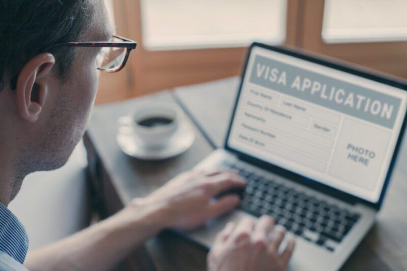 Primer plano de un hombre solicitando un visado online en su ordenador portátil.