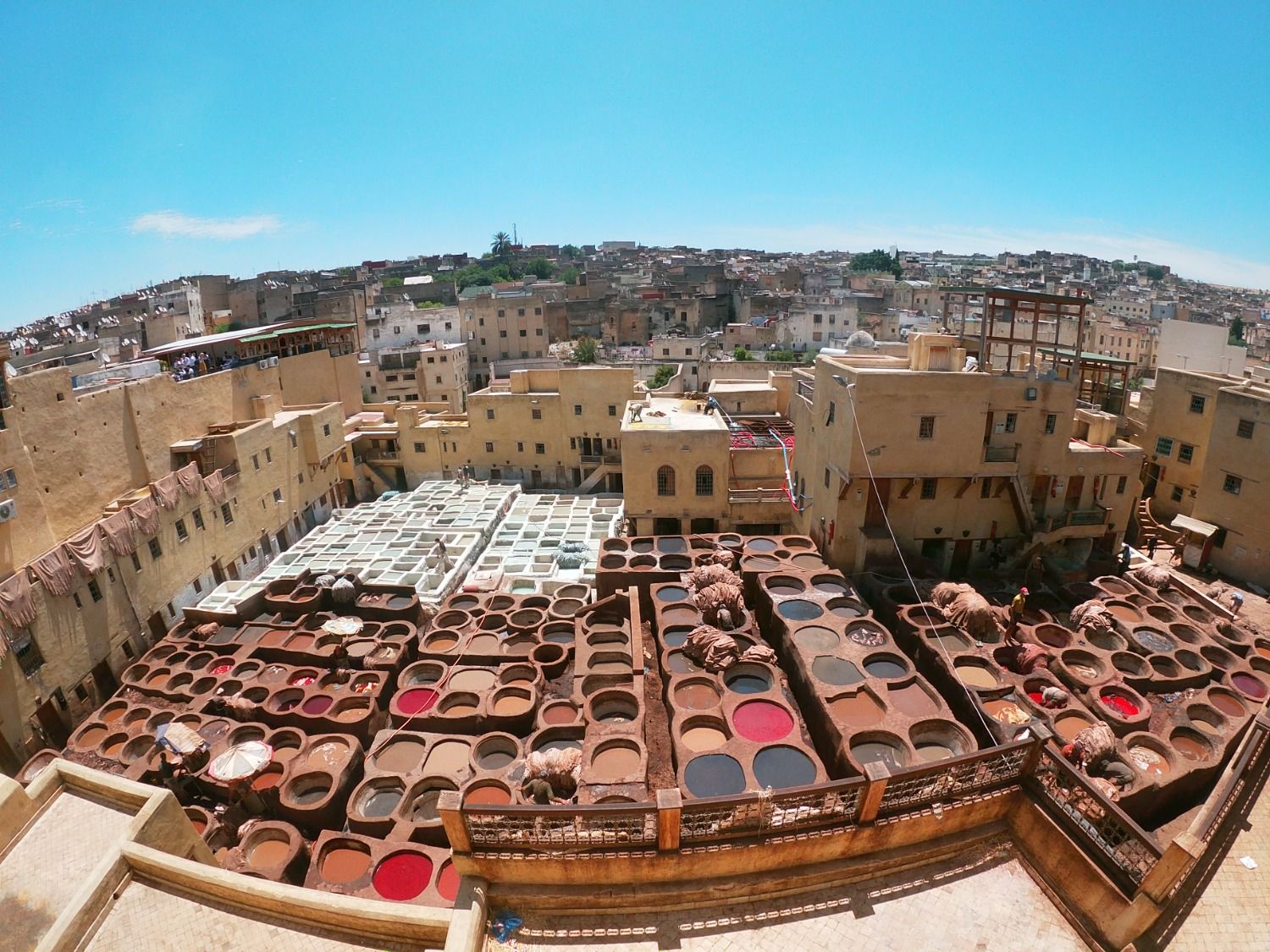 Vista panorámica desde lo alto de las curtidurías de Fez, mostrando los icónicos pozos circulares llenos de tintes de colores vibrantes y cueros secándose bajo el sol.