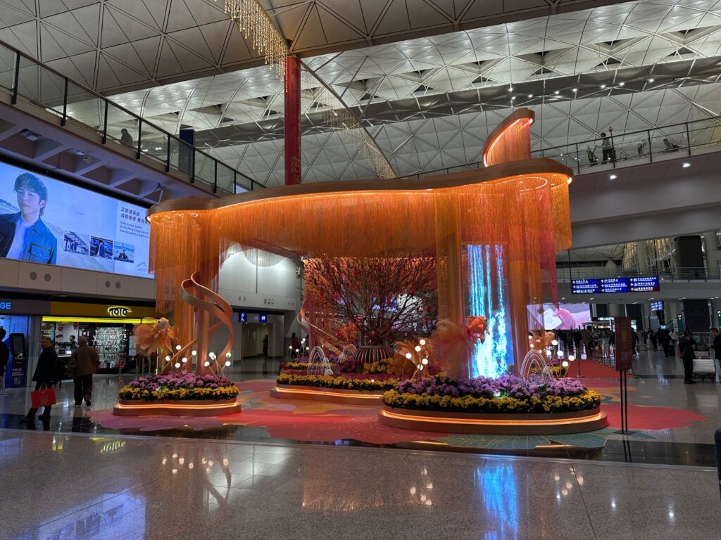 Una instalación decorativa iluminada en tonos naranja y flores en la terminal del Aeropuerto Internacional de Hong Kong.