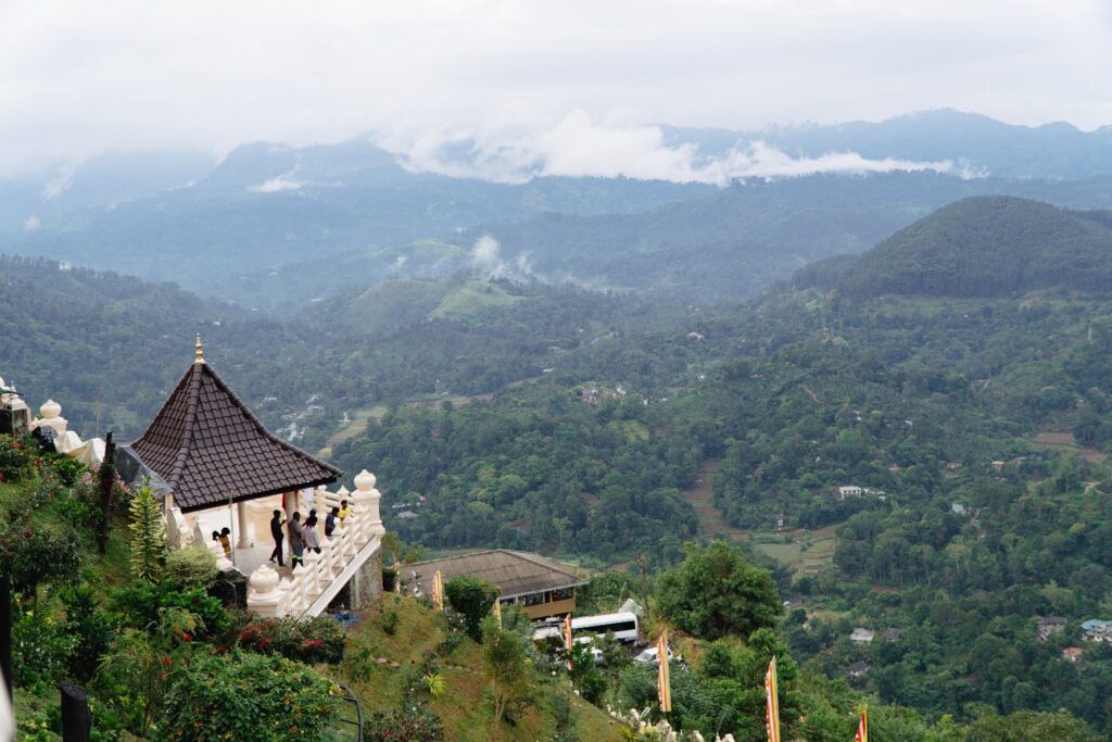 Un templo con techo puntiagudo en la ladera de una montaña verde y brumosa en Sri Lanka.