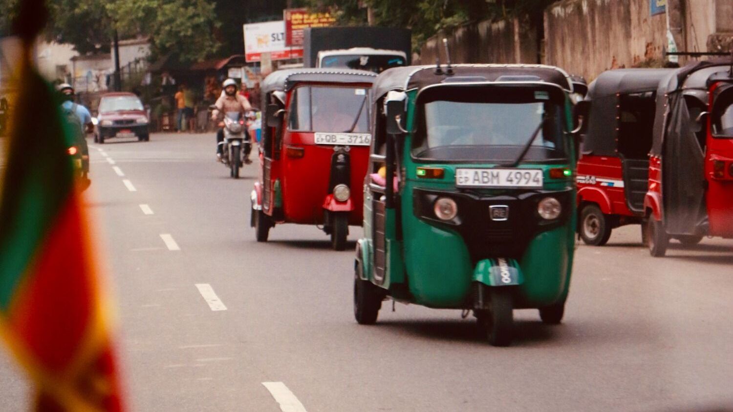 Varios tuk-tuks de colores circulando por una calle concurrida en Sri Lanka.