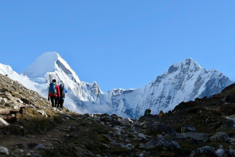 Excursionistas en camino hacia las cumbres, rodeados de paisajes rocosos y nevados.