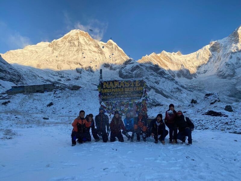 Grupo de excursionistas posando en el campamento base del Annapurna, rodeados de nieve y montañas.