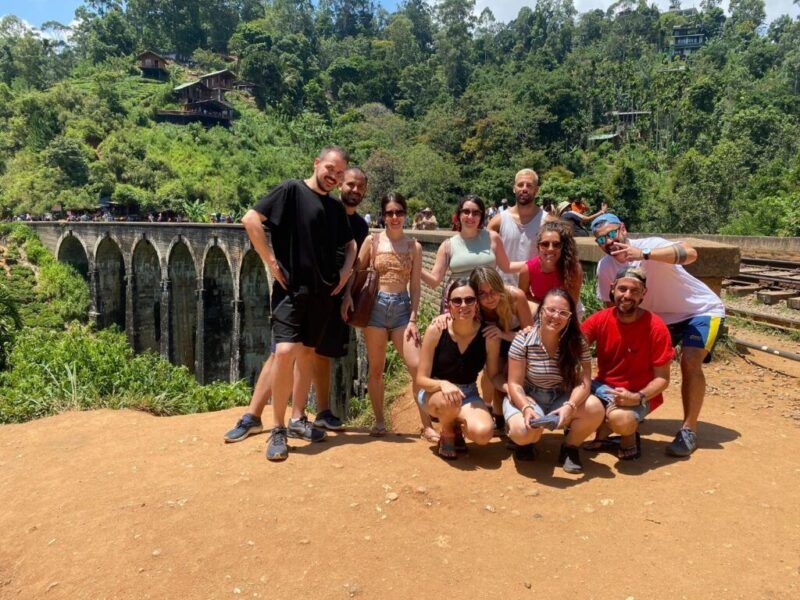 Un grupo de viajeros de WeRoad posa frente al famoso Puente de Nueve Arcos en Ella, Sri Lanka.