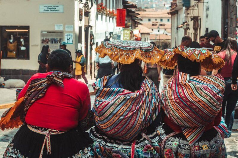 Mujeres con coloridos trajes tradicionales en las calles de Cusco, Perú, que reflejan el patrimonio cultural.