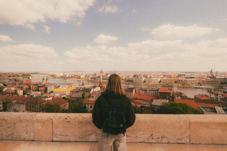 Viajera con mochila de espaldas contemplando el panorama de Budapest desde la Colina del Castillo, con el río Danubio y el Parlamento al fondo