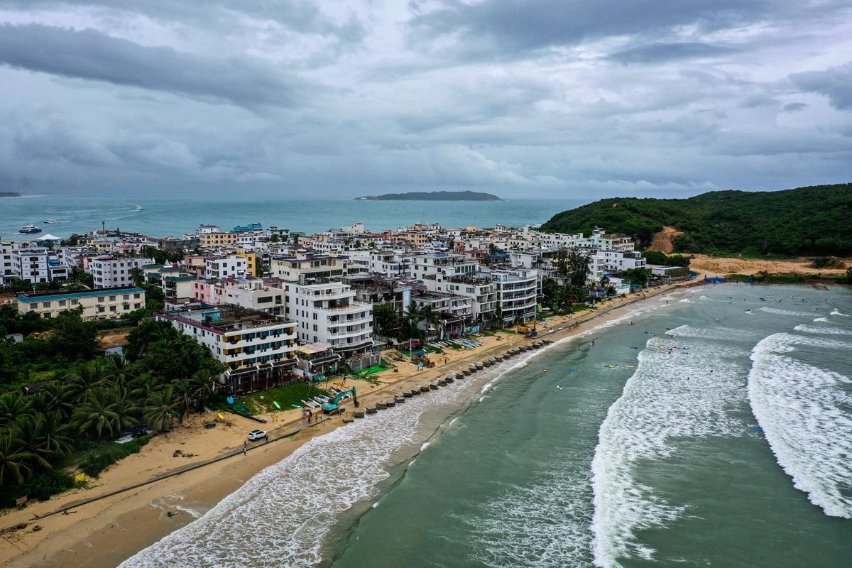 Costa de Sanya vista desde arriba con edificios junto a la playa, oleaje y colinas verdes