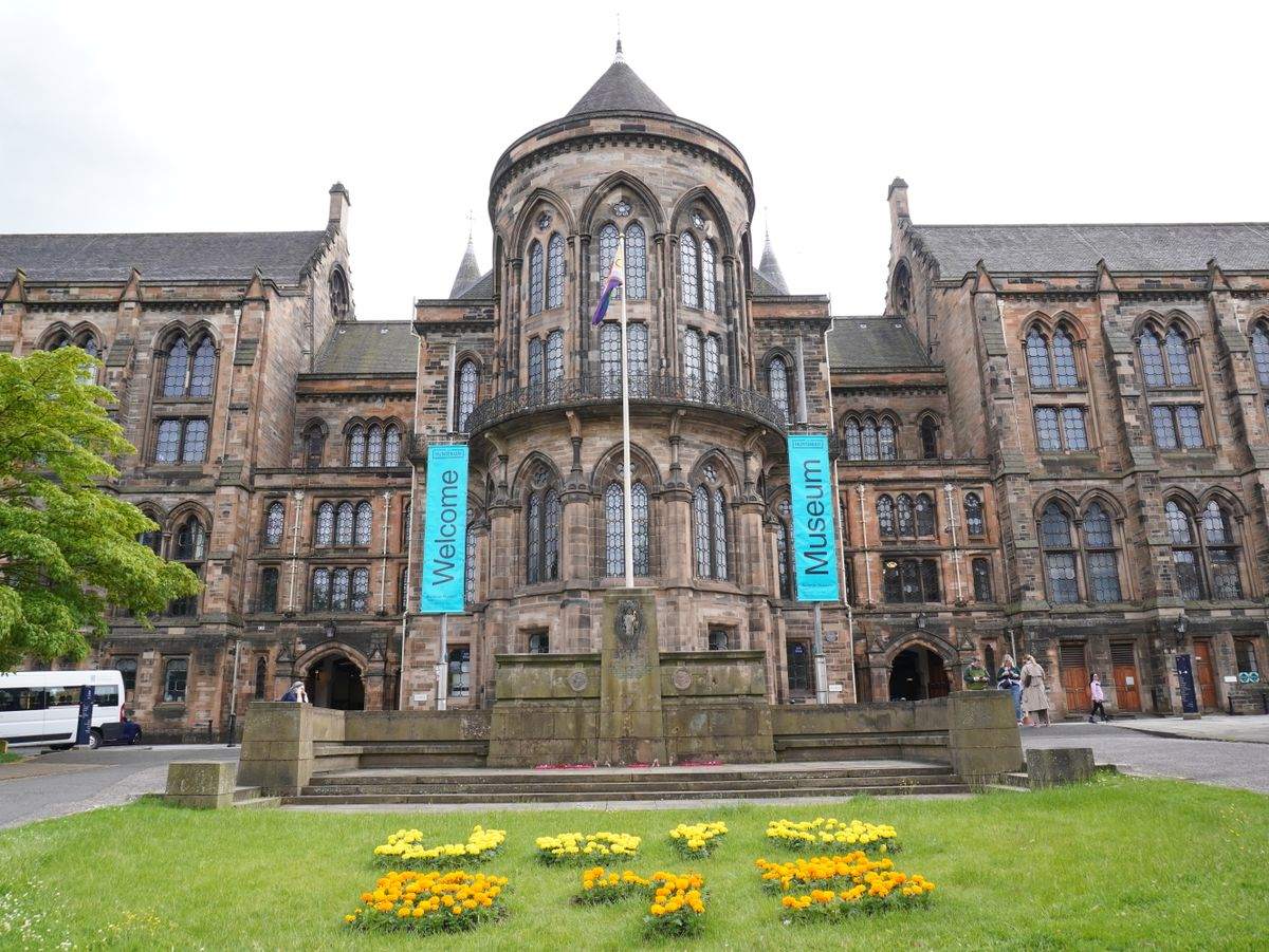 Fachada histórica de la Universidad de Glasgow con banderolas del museo y jardín frontal