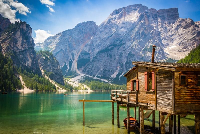 Casa de madera sobre pilotes con contraventanas rojas en el lago Braies, rodeada de montañas de los Dolomitas