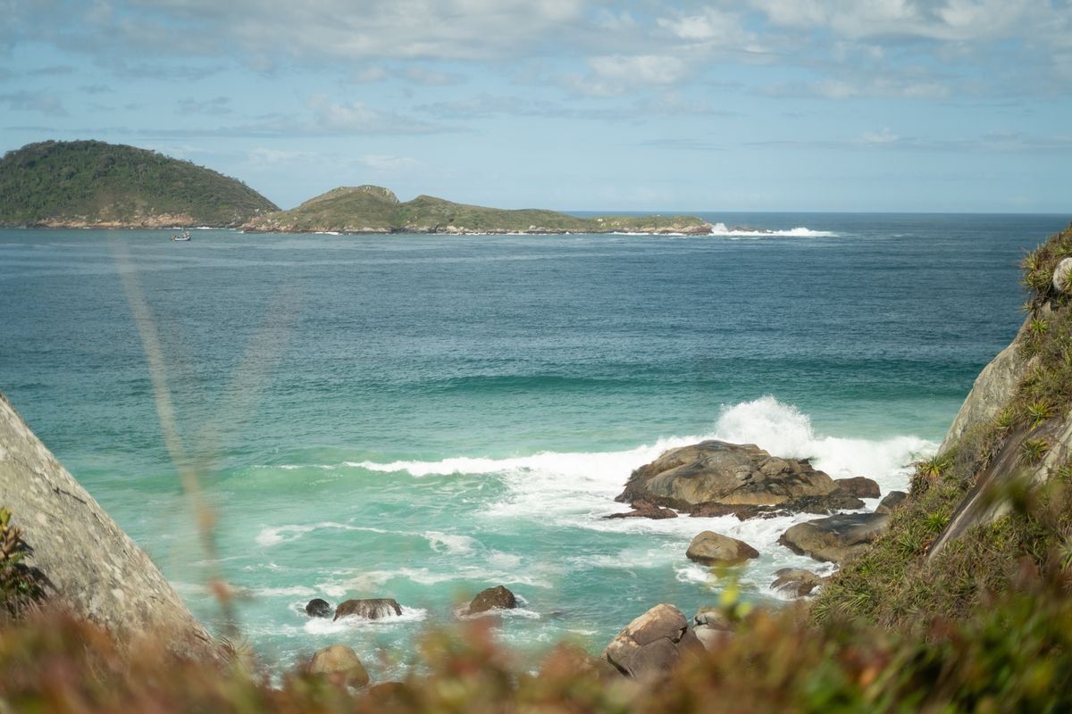 Mar turquesa con olas rompiendo entre rocas y pequeñas islas en el horizonte