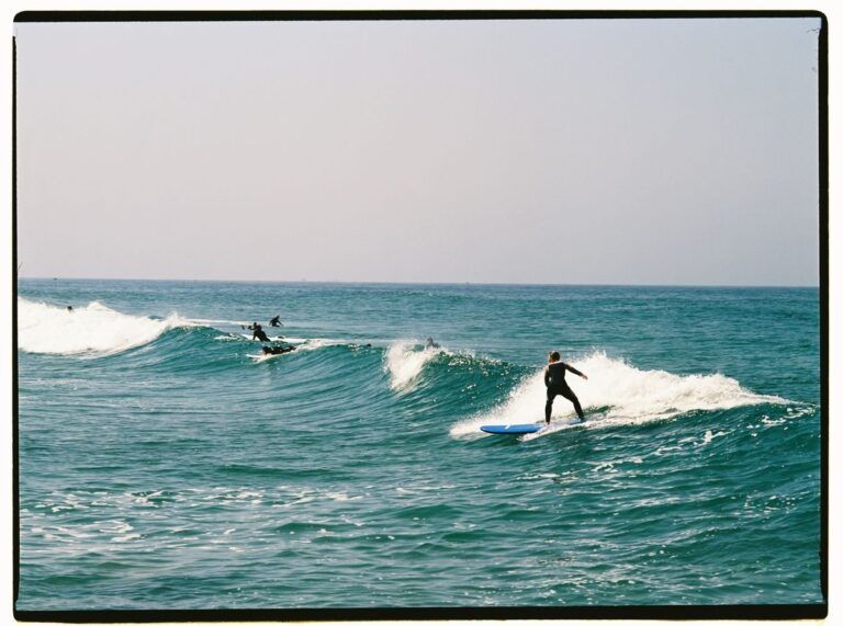 Surfistas sobre varias olas en el mar durante un día despejado.