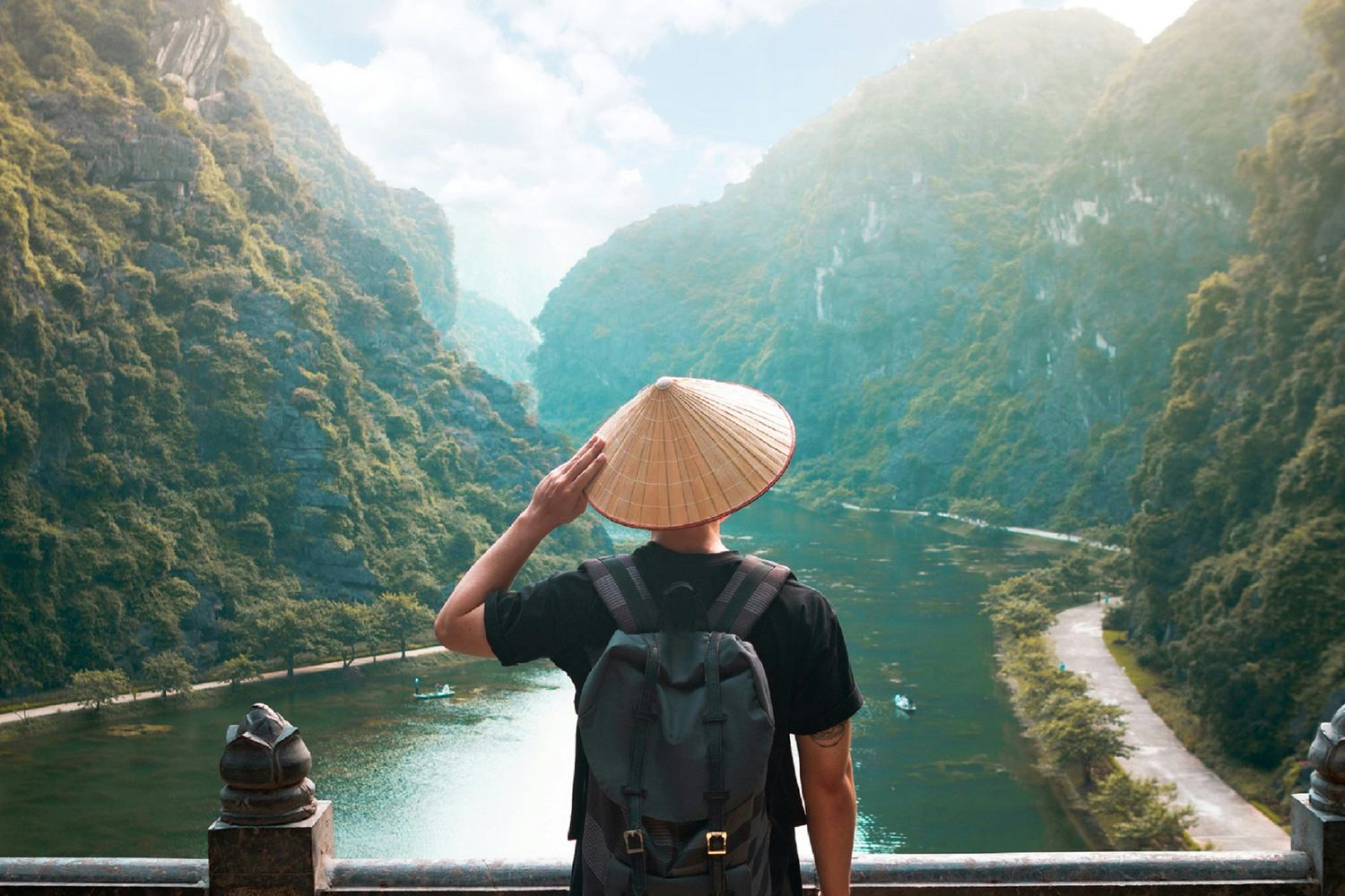 Viajero de espaldas con sombrero cónico vietnamita contempla el valle kárstico de Trang An, Vietnam
