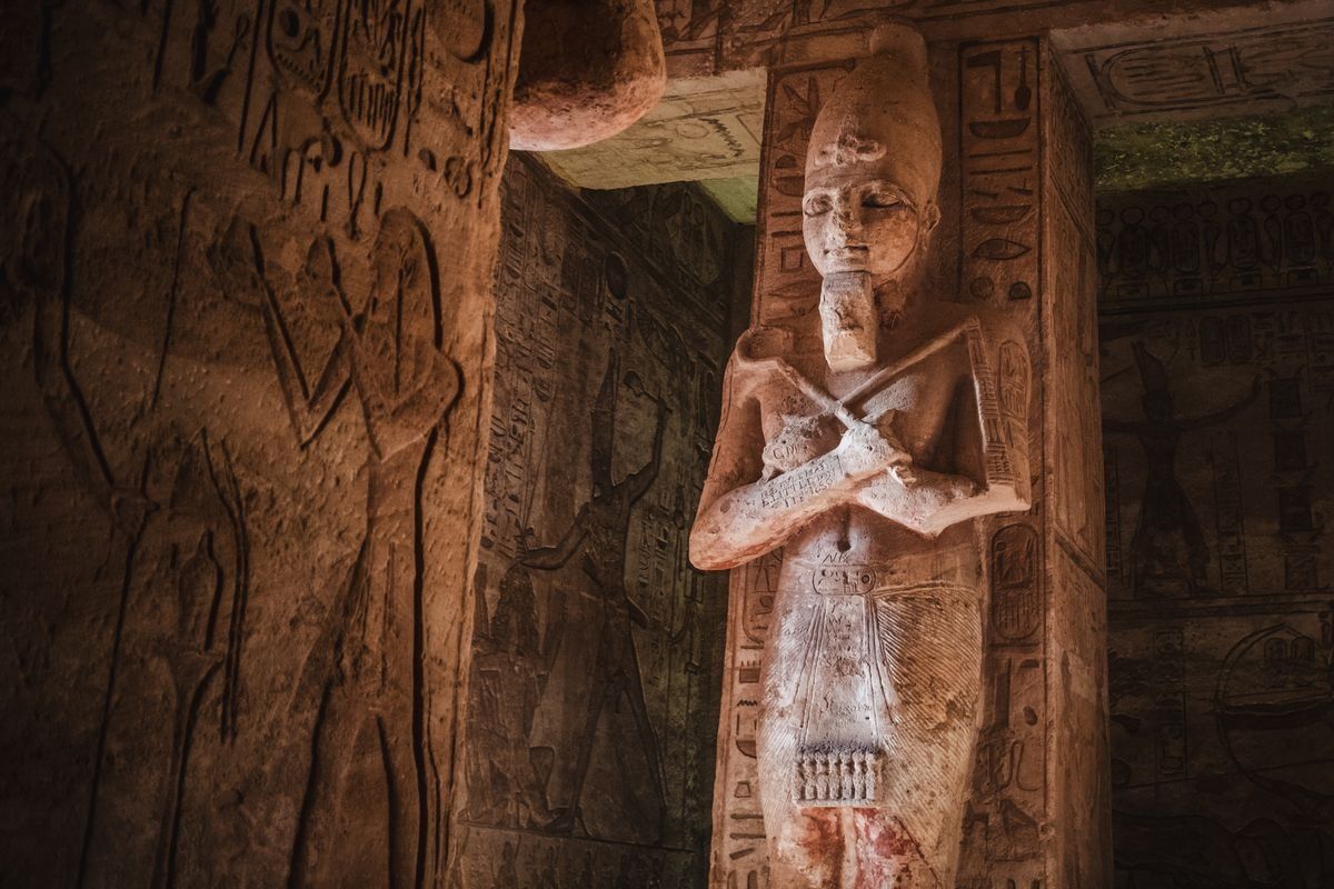 Estatua faraónica entre muros con jeroglíficos en una tumba egipcia