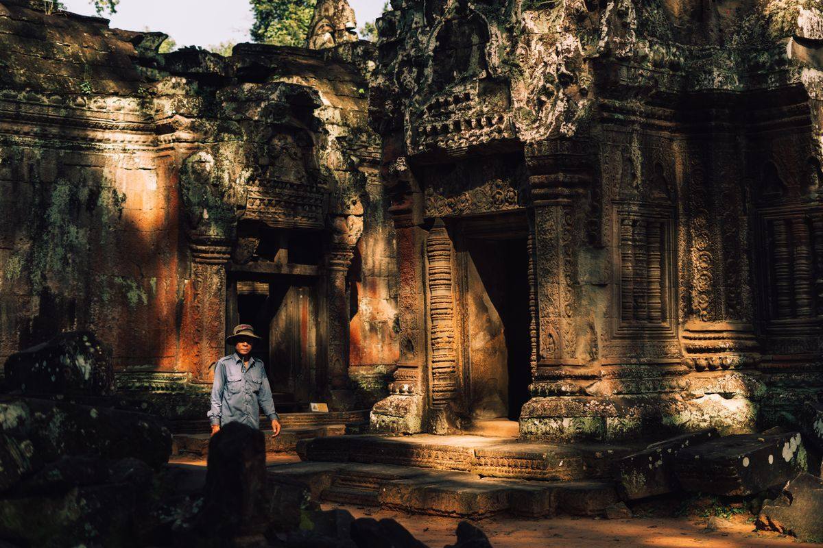 Visitante frente al antiguo templo de piedra Ta Prohm con relieves tallados
