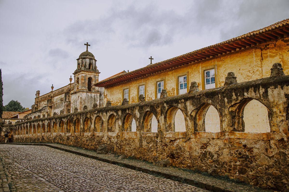 Iglesia antigua con arcadas de piedra junto a una calle empedrada