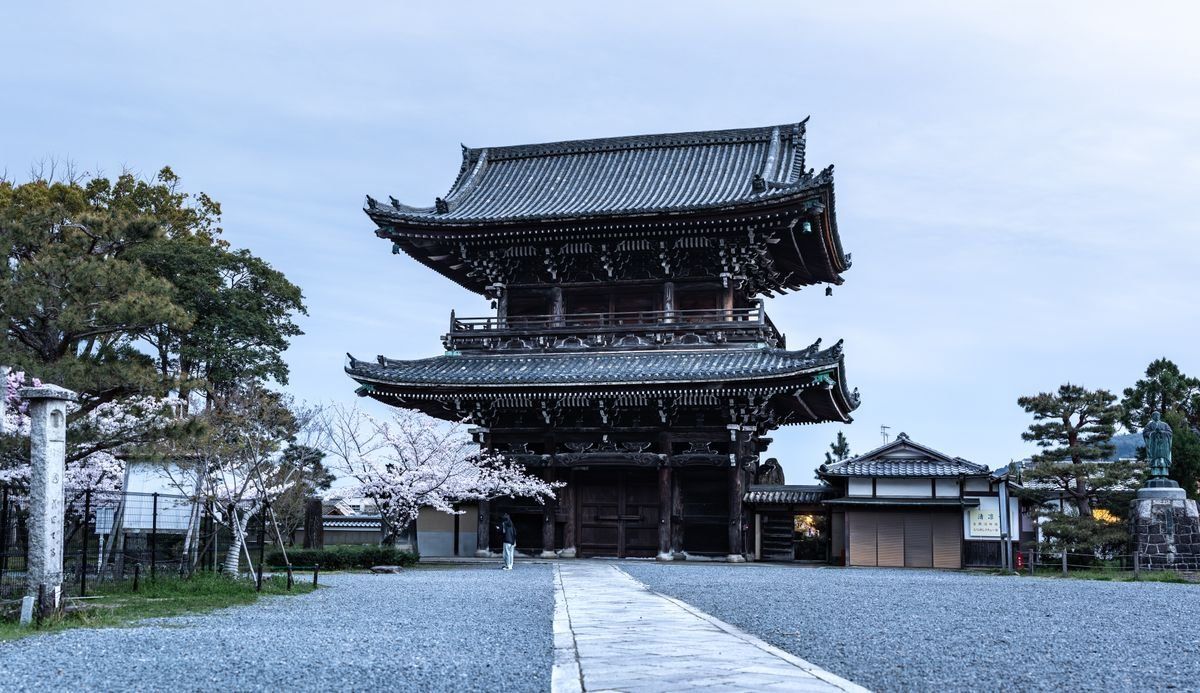 Pagoda japonesa tradicional junto a un camino de grava y cerezos en flor