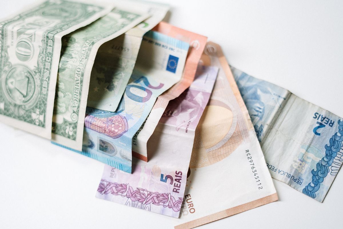 Billetes de dólar, euro y real brasileño sobre fondo blanco
