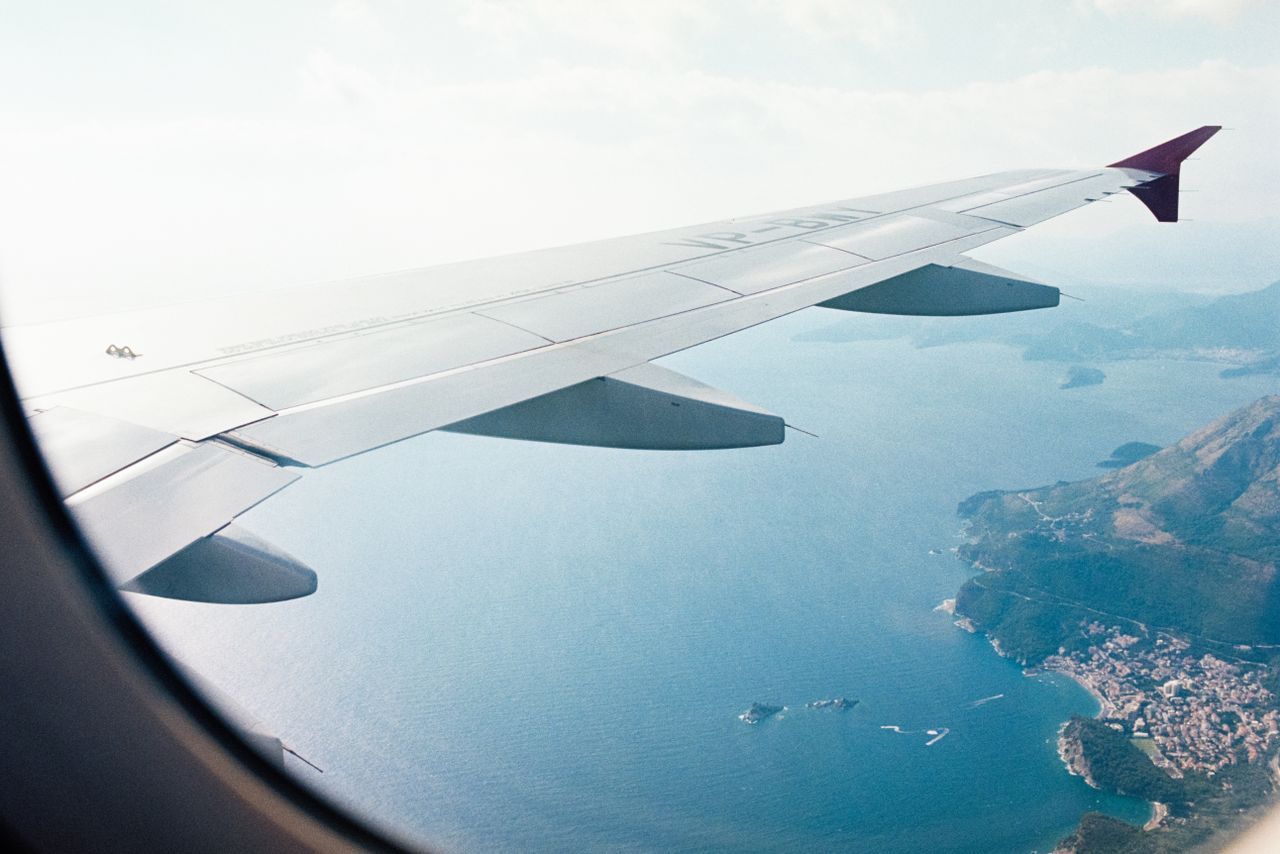 Black Friday vuelos: ala de un avión volando sobre la costa