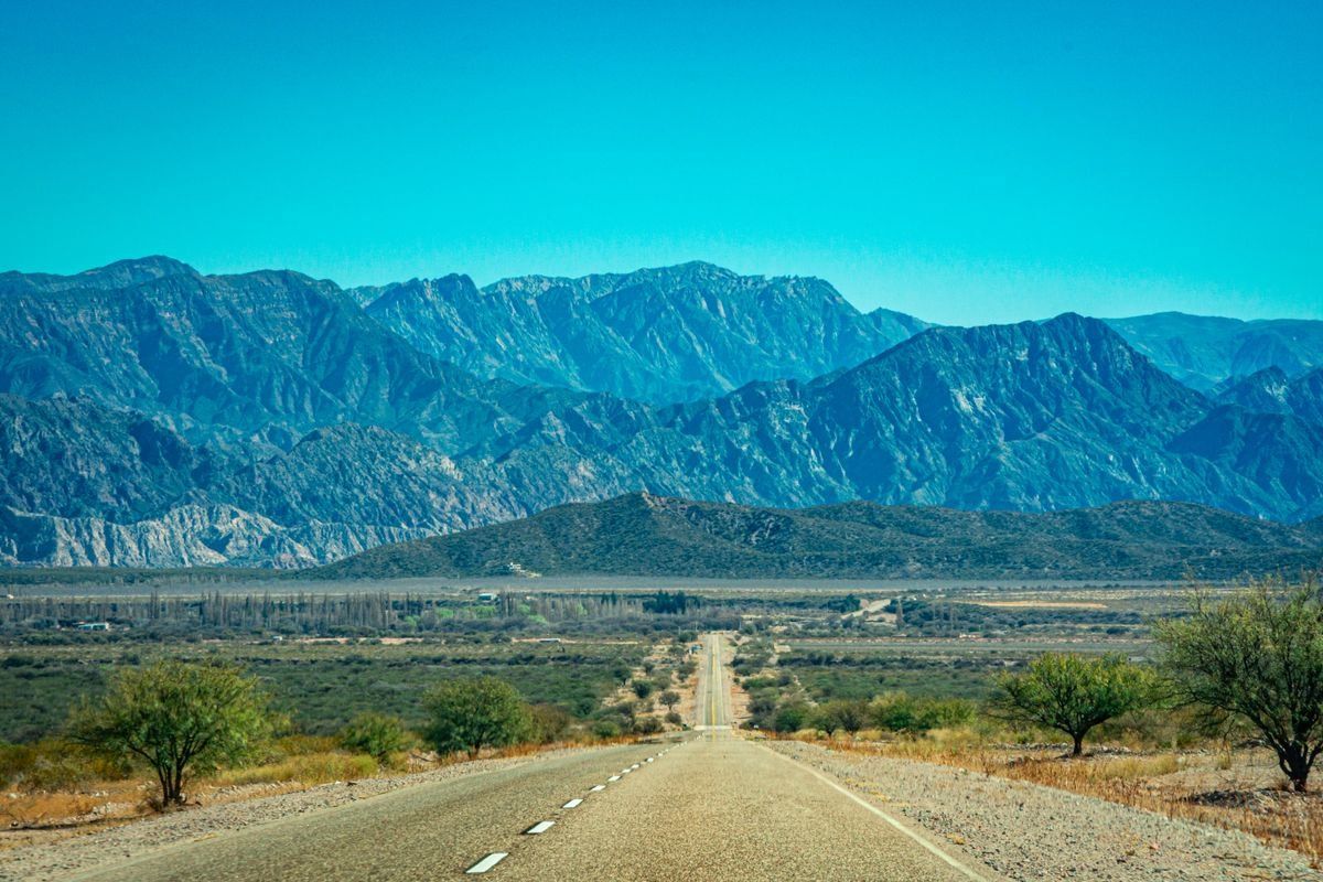 Carretera recta entre paisaje árido con montañas al fondo