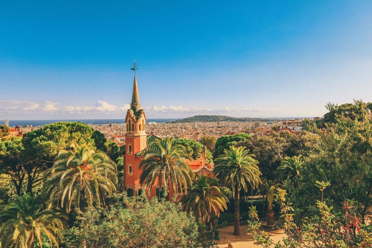 Casa rosada de Park Güell rodeada de palmeras y jardines con panorámica de Barcelona
