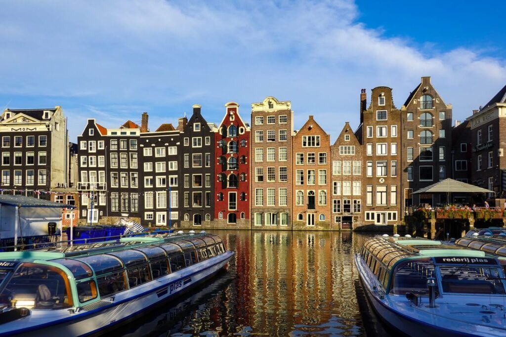 Casas típicas y barcos en el canal Damrak de Ámsterdam