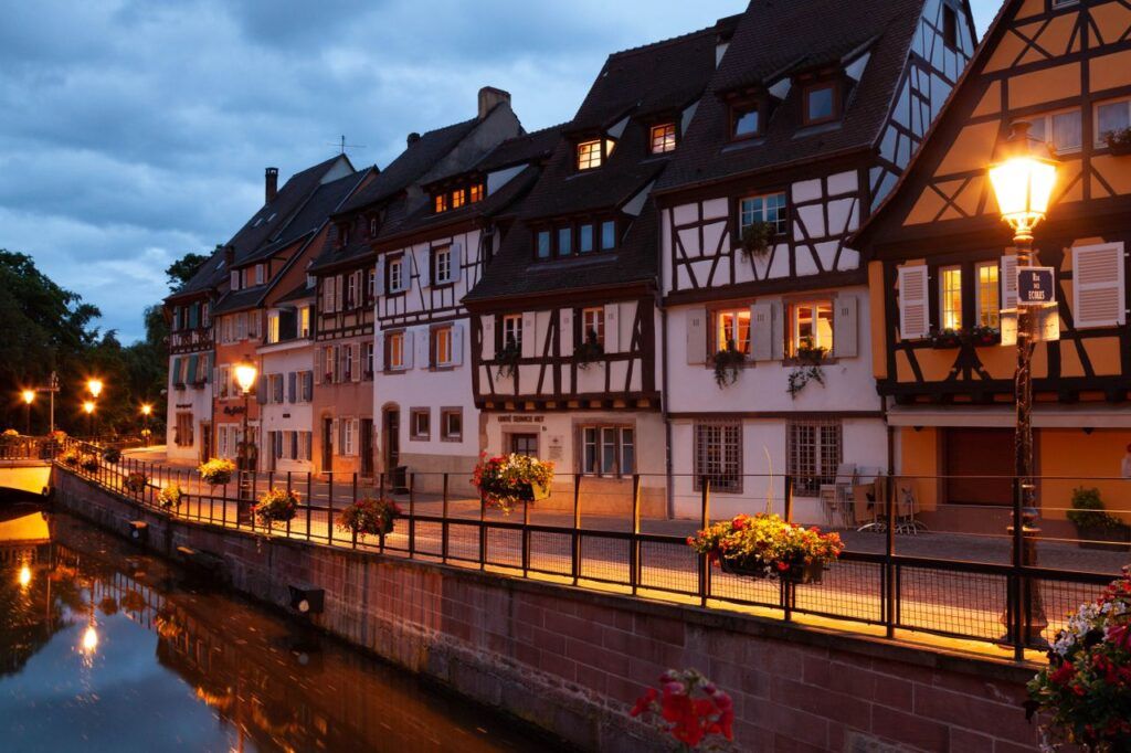Casas de entramado de madera iluminadas junto al canal de Colmar al anochecer