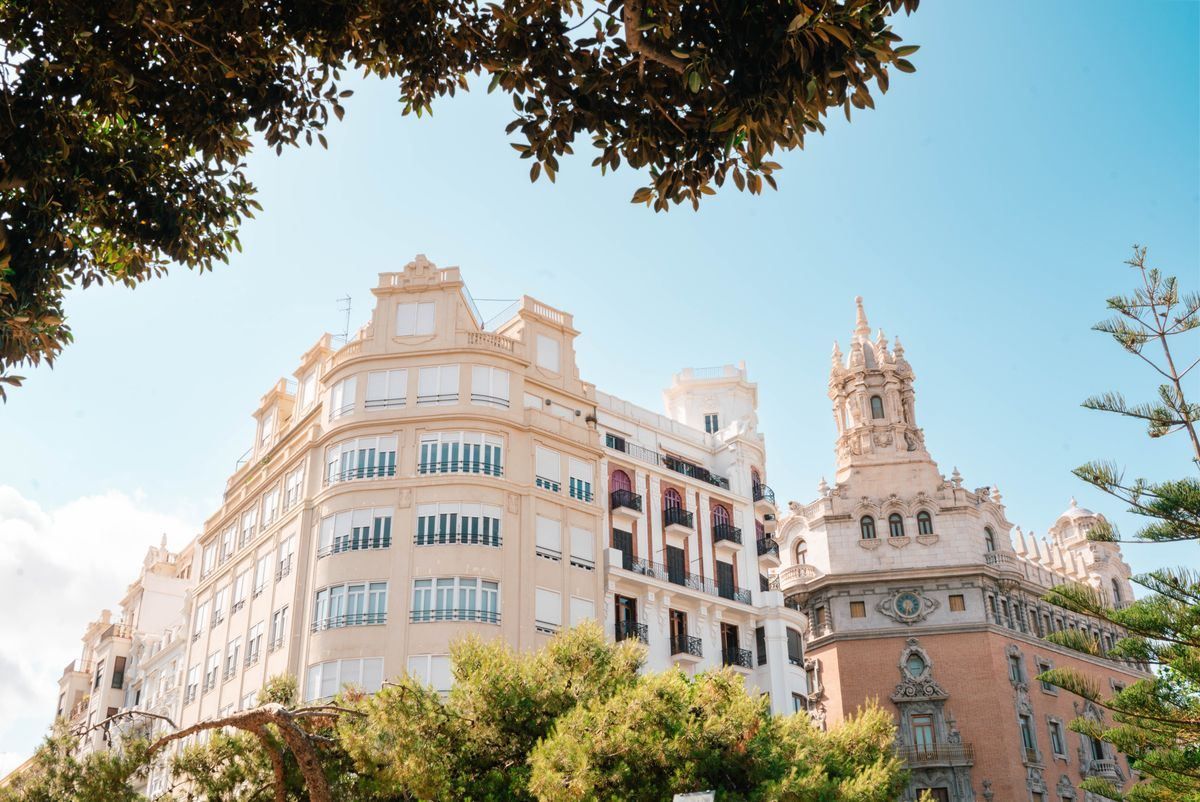 Edificios históricos de Valencia entre árboles, con torre ornamental y cielo azul