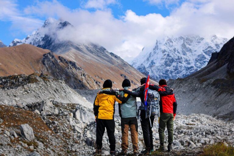 Cuatro senderistas frente a montañas nevadas en una ruta donde puede aparecer el mal de altura