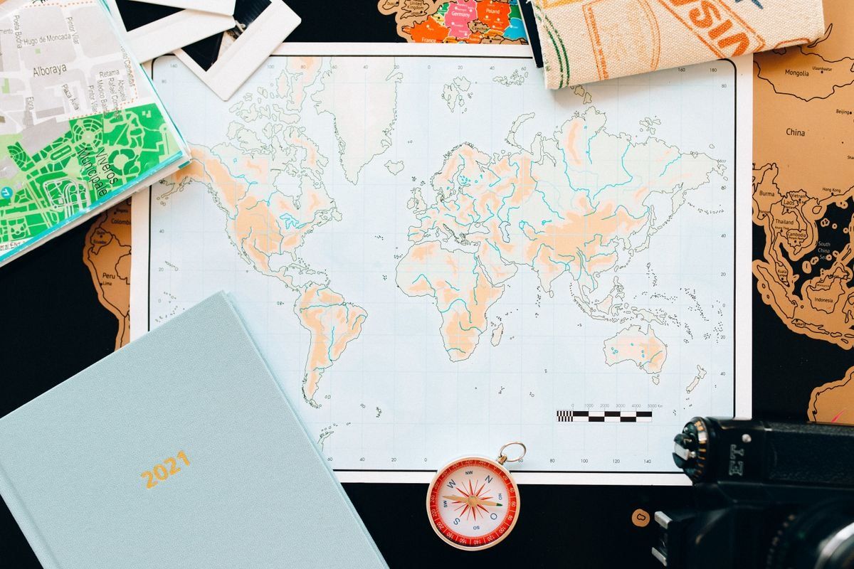 Mapa del mundo sobre una mesa con brújula, agenda y objetos de viaje