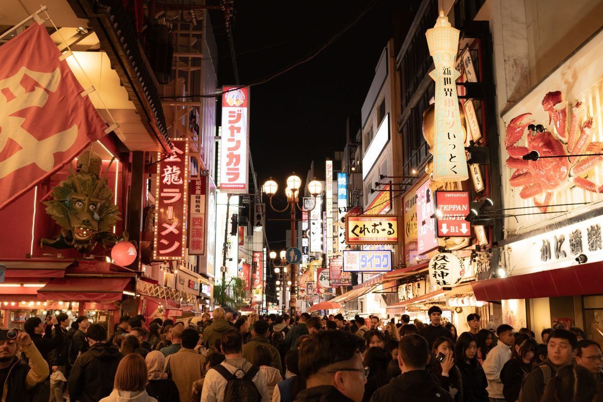 Multitud caminando por una calle iluminada de Dotonbori entre restaurantes y carteles brillantes