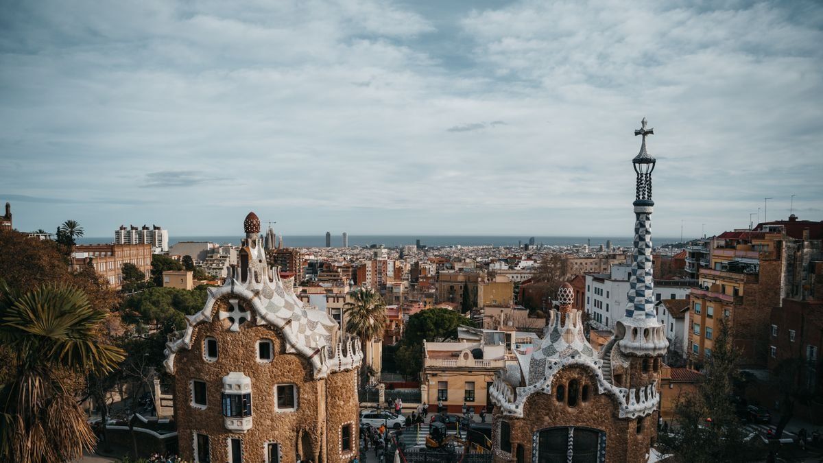 Pabellones de Park Güell con torres decoradas y skyline de Barcelona al fondo
