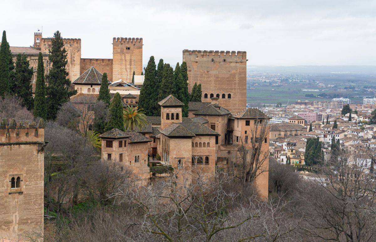 Palacios y torres de la Alhambra entre cipreses con la ciudad al fondo