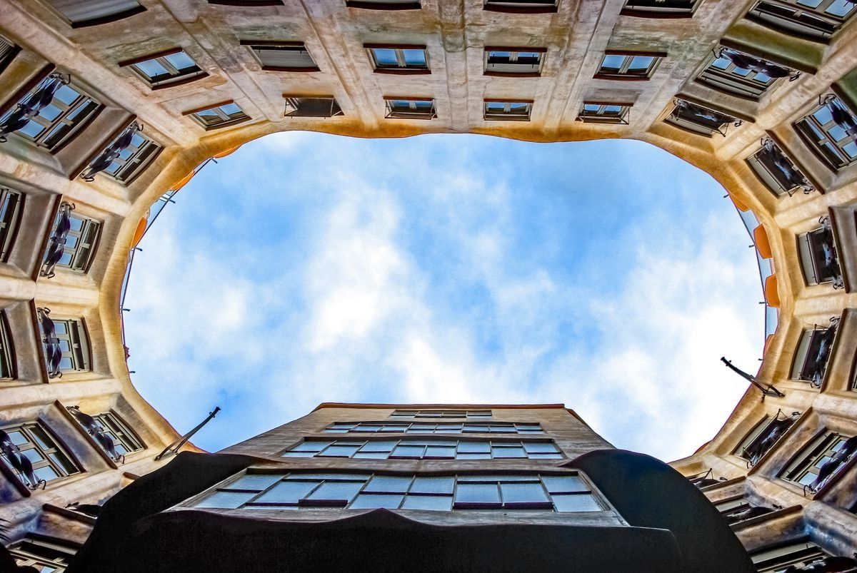 Patio interior de La Pedrera visto desde abajo con cielo azul en el centro