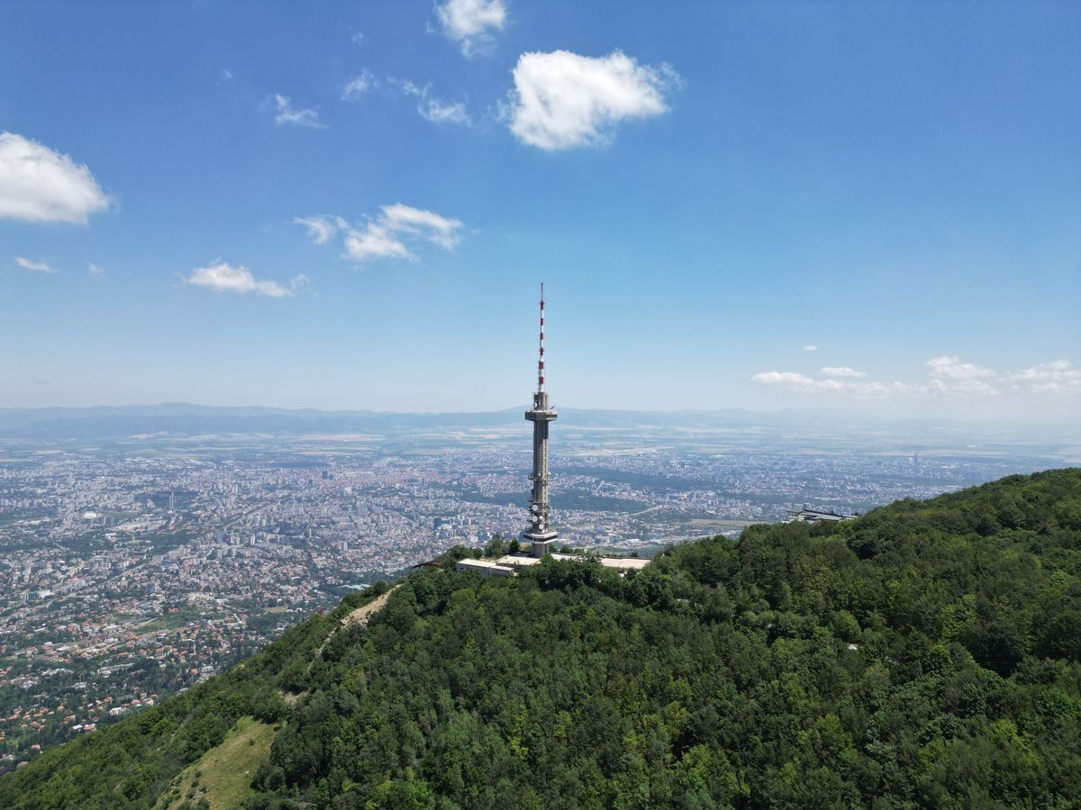 Torre de televisión en la montaña Vitosha sobre una ladera boscosa con Sofía al fondo