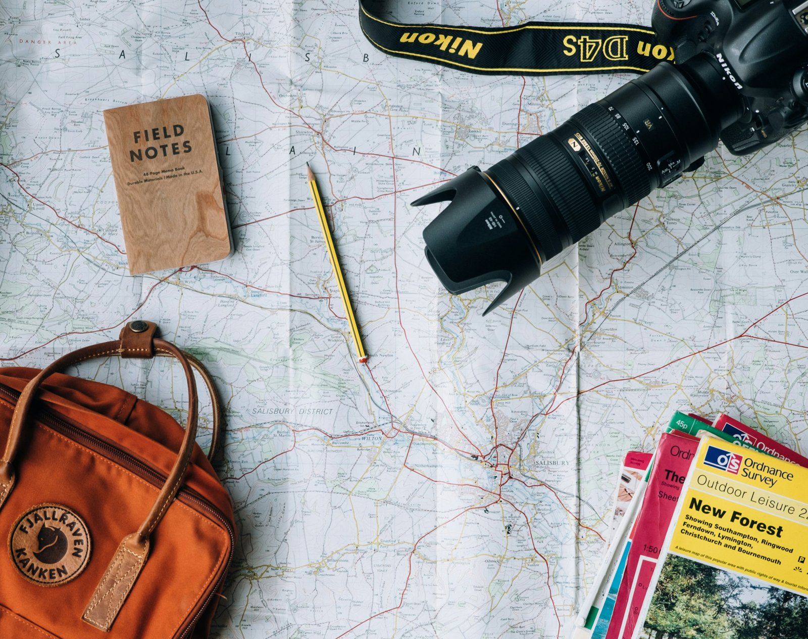 Mapa, cámara, libreta y mochila listos para planificar un viaje