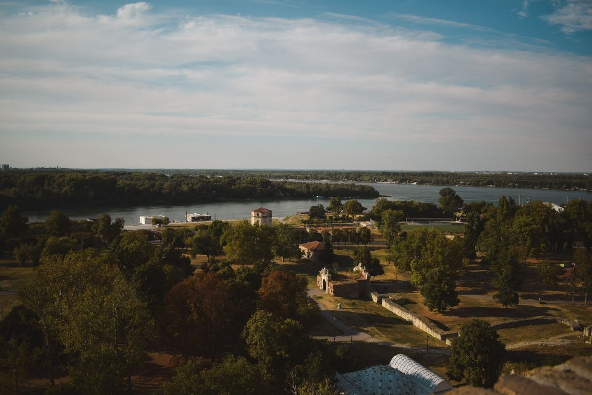 Vista elevada de un parque arbolado con el Danubio al fondo bajo un cielo azul